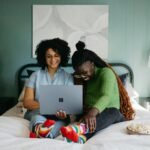 Woman using a laptop on a bed at home, illustrating a laptop buying guide for 2026